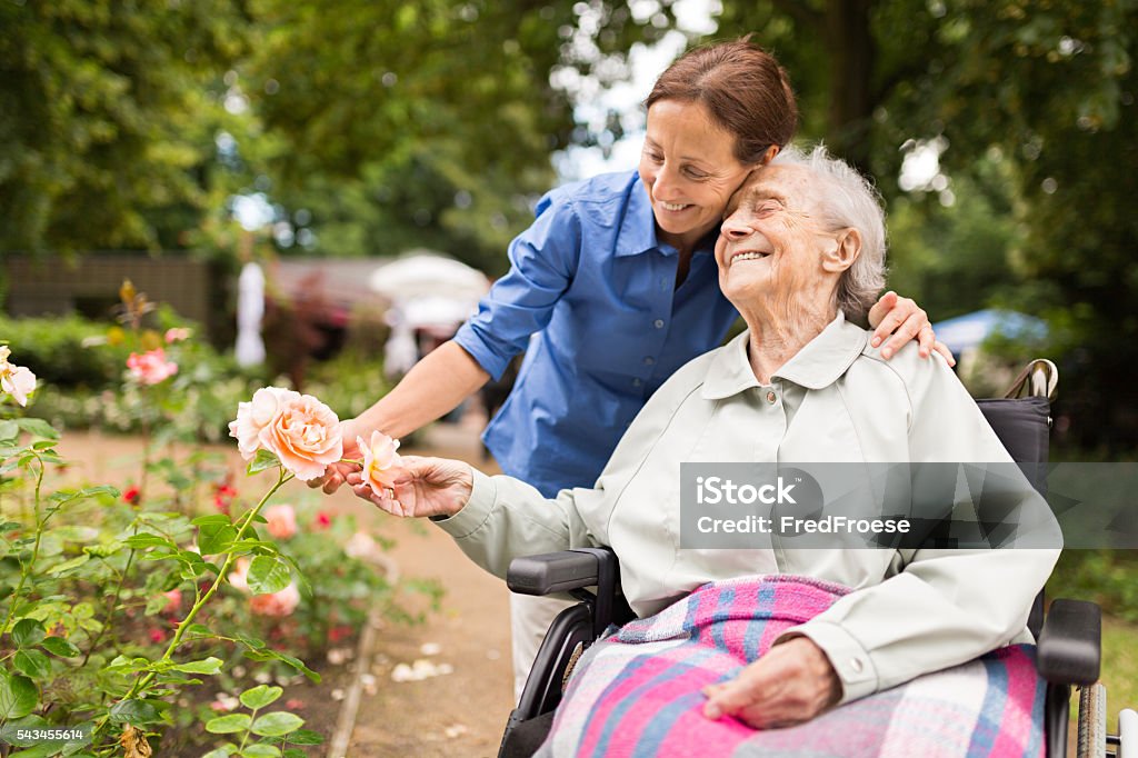 Senior Frau sitzt auf einem Rollstuhl mit Der Fürsorgliche - Lizenzfrei Fürsorglichkeit Stock-Foto