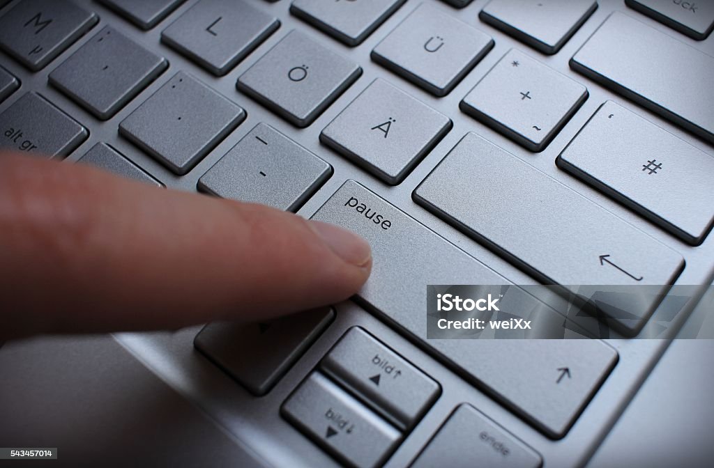 En appuyant sur le bouton de rupture sur un clavier QWERTZ argenté allemand. - Photo de Bouton poussoir libre de droits