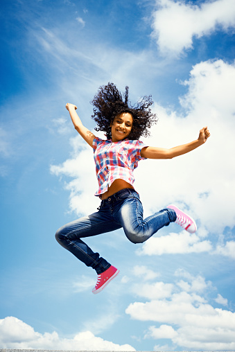 Youth Culture. Carefree teenage girl with outstretched arms jumping. She feeling happiness and joy. She is in mid-air. It is perfect for using it in commercial and advertising photography, reports, books, presentation