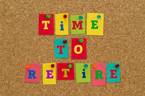 TIME TO RETIRE message written on colorful sticky notes pinned on cork board.