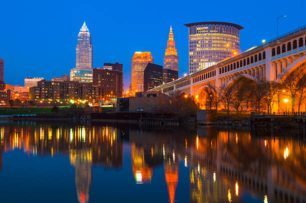 Cleveland Skyline with Bridge and River at Dusk Downtown Cleveland skyline at dusk with a bridge on the left and  the Cuyahoga River with skyline reflections below. cuyahoga river photos stock pictures, royalty-free photos & images