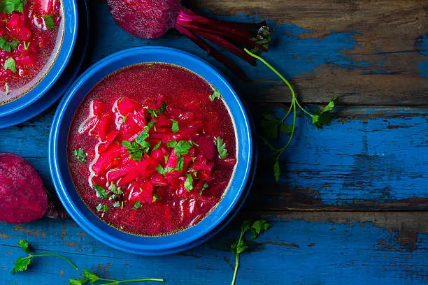 Russian and Ucrainian traditional vegetarian red soup - borsch in blue plates on wooden background. Top view
