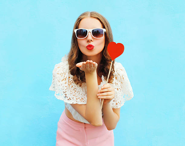 mujer con piruleta de corazón rojo envía beso de aire encima - kissing blowing a kiss blowing women fotografías e imágenes de stock