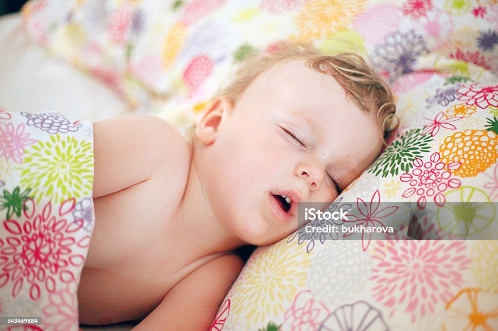 Petit garçon dormant dans le grand lit - Photo de Bouche ouverte libre de droits