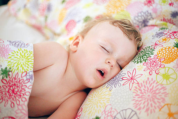 Little boy sleeping in the big bed Cute little Caucasian boy with blond hair sleeping in a big bed on the pillow and covered with blanket. Little boy sleeping with his mouth open. Sweet dreams. Little boy in his parent's bed. Toddler a the big bed. napping photos stock pictures, royalty-free photos & images