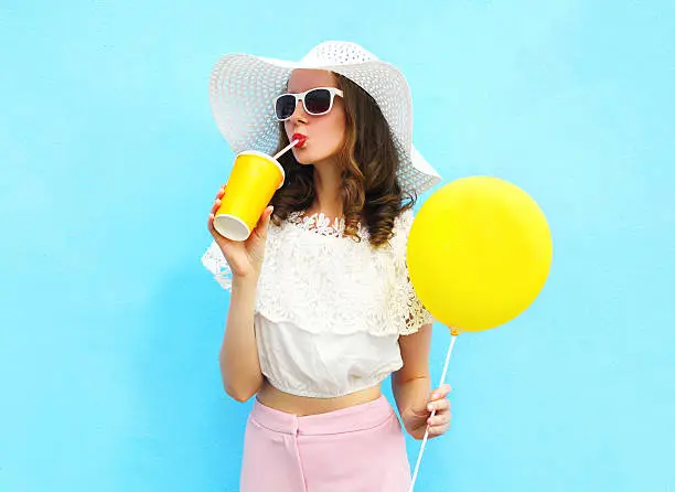 Photo of woman in straw hat with balloon drinks fruit juice cup