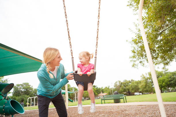 süße mutter und tochter spaß haben auf der schaukel - playground cute baby blue stock-fotos und bilder