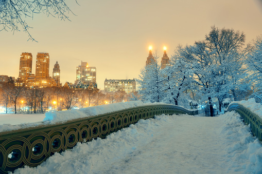 Central Park winter with skyscrapers and Bow Bridge in midtown Manhattan New York City