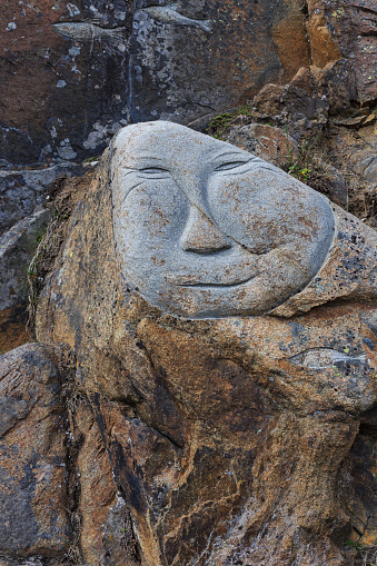 Face carved on stone The diversity underpins'm sad, angry, happy as public art in the city, walking along the street.