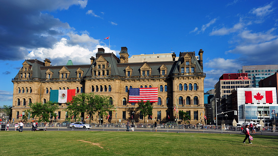 Ottawa, Canada - June 29, 2016:  The Langevin Block, a National Historic Site, was covered with a Mexican and US flag for the visit of the US and Mexican presidents, known as The Three Amigos Summit.  Many people gathered at Parliament Hill to try and catch a glimpse of the leaders and to hear the speeches on the big screens on the site.