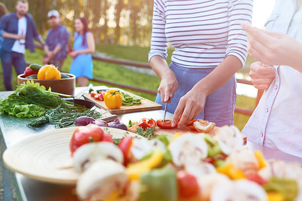 Preparing food outdoors One women cutting pepper on cutting board, her friend putting food on stick chopped dill stock pictures, royalty-free photos & images