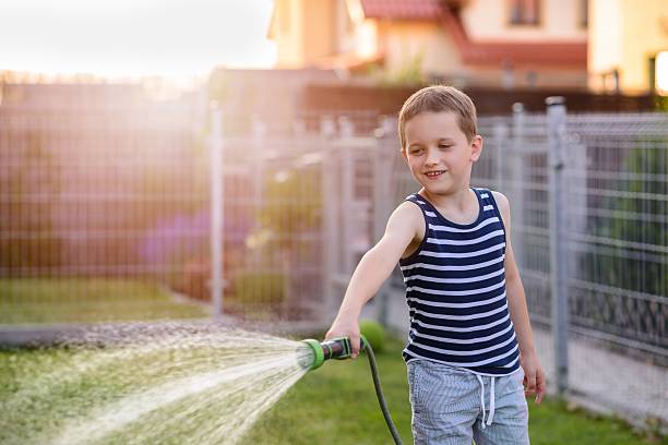 istock Little boy child watering grass in garden. 543558830