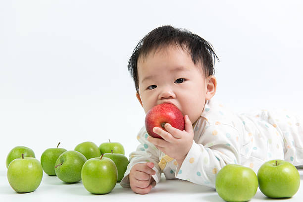 Asian baby eating red apple on white background
