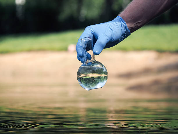 ręka w rękawiczce trzymająca retortę z czystą wodą - impurities zdjęcia i obrazy z banku zdjęć