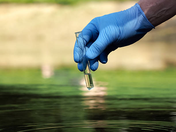 Hand in glove holding a test tube of clear water Water sample. Hand in glove holding a test tube of clear water. Concept - water purity analysis, environment, ecology. Water testing for infections, permission to swim vibrio stock pictures, royalty-free photos & images