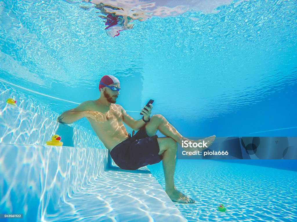 Addicted to social networking: with mobile phone underwater Workaholic man underwater, social networking on the mobile phone. He is surrounded by small yellow plastic ducks Telephone Stock Photo