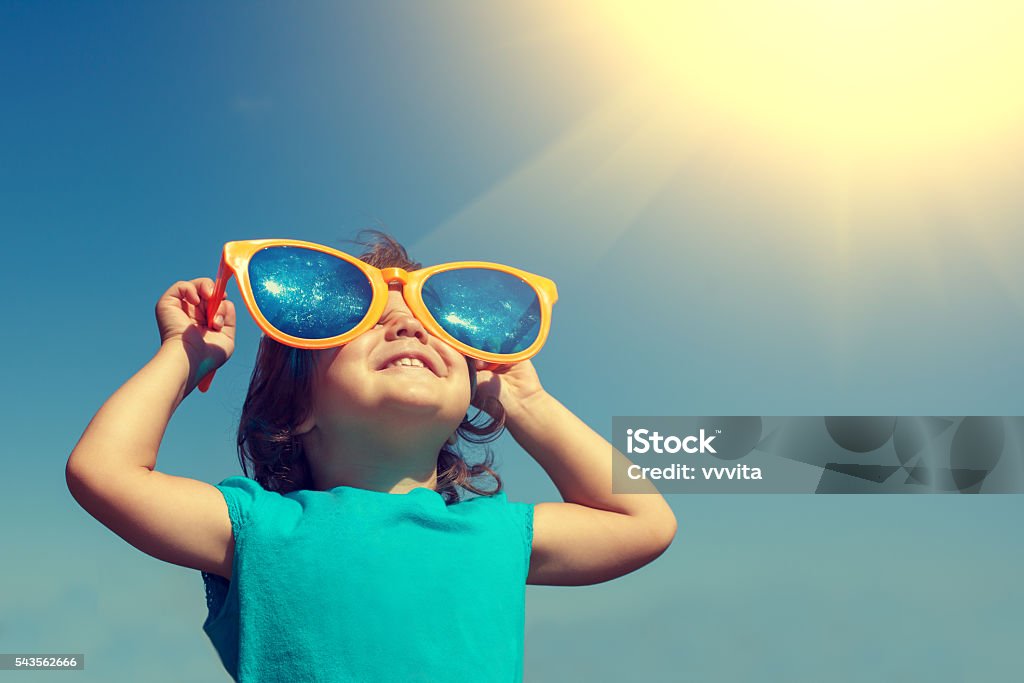 Fillette heureuse avec de grandes lunettes de soleil à la recherche au coucher du soleil - Photo de Enfant libre de droits