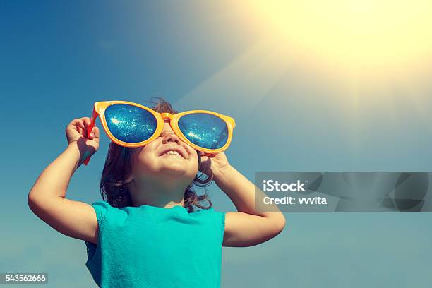 Foto de Menina Feliz Com O Grande Óculos De Sol Olhando Para O Sol e mais fotos de stock de Criança
