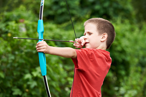 Little archer with bow and arrow outdoors