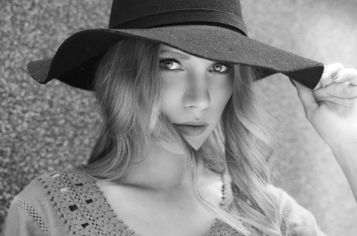 Beautiful portrait of fashionable young woman with hat and beautiful hair. Black and white photo.