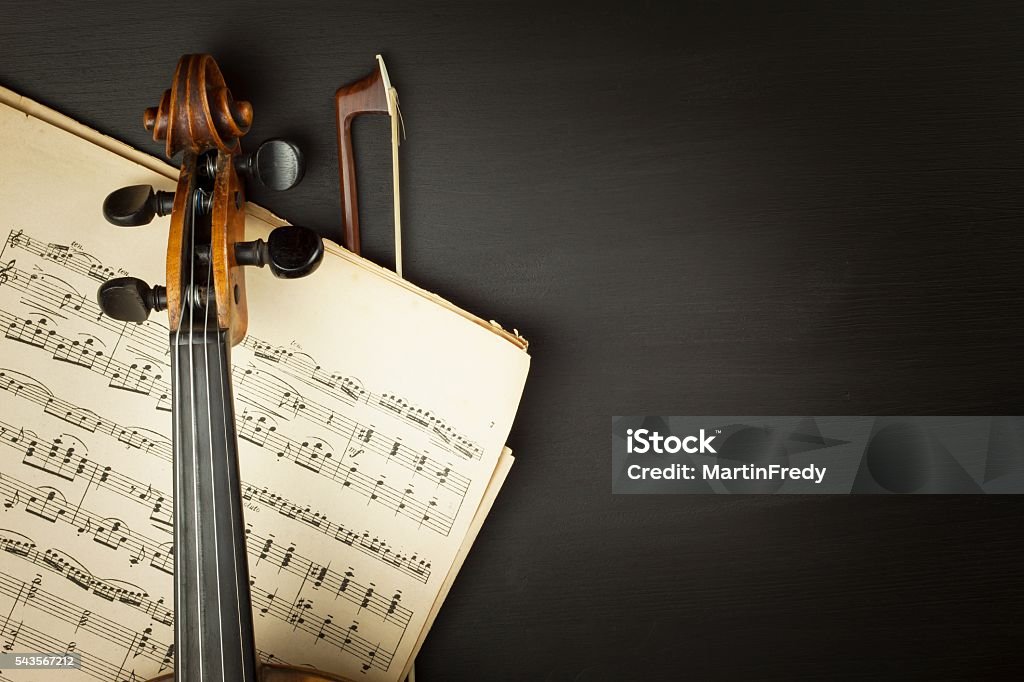 Old violin on dark wooden table Old violin on dark wooden table. Detail of old violin on a black background. Invitation to the Violin Concerto. Classical Music Stock Photo