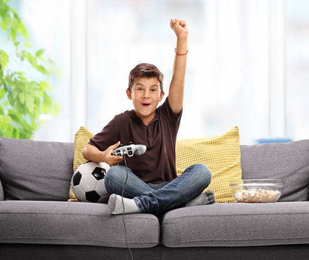 ragazzo gioioso che gioca a videogiochi di calcio - little boys people indoors soccer foto e immagini stock