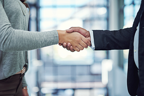 Cropped shot of a businessman and businesswoman shaking hands in an office