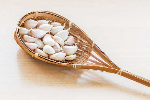 garlic in bamboo basket on wooden table