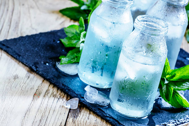 cold mineral water with ice Very cold mineral water with ice in a misted glass bottles, dark background, selective focus refreshment stock pictures, royalty-free photos & images