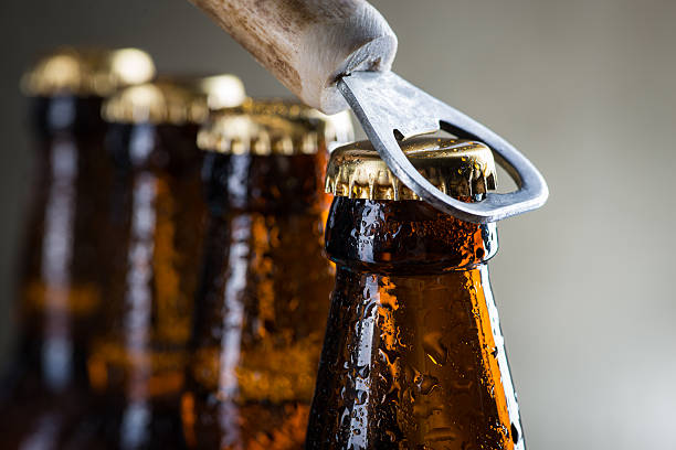 Glass beer bottle and opener on the textured brown table, copy space