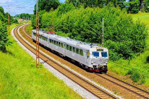 Norsholm, Sweden - June 20, 2016: Gray train passing on a double tracked railway on the countryside. Train is called run by SJ and is heading for Linkoping.