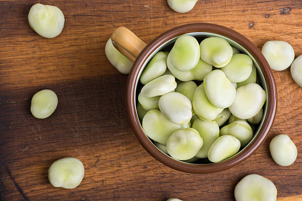 Fresh broad beans in bowl on wooden board stock photo