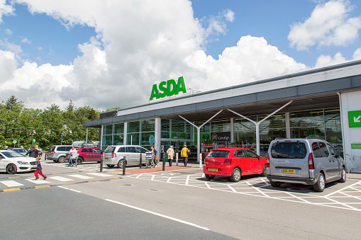 Road in front of Edinburgh Airport main terminal building. Passengers are standing in front of its entrance. The airport is six miles west of Edinburgh city center.