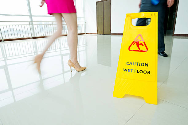 Yellow caution wet floor sign standing on a blue and white checkered floor, warning of slippery conditions