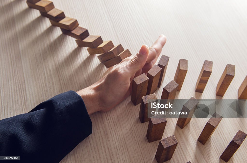 Solution Businesswoman hand stopping the domino wooden effect concept for business. Domino Stock Photo