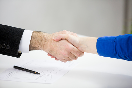 Close up of business people shaking hands at desk