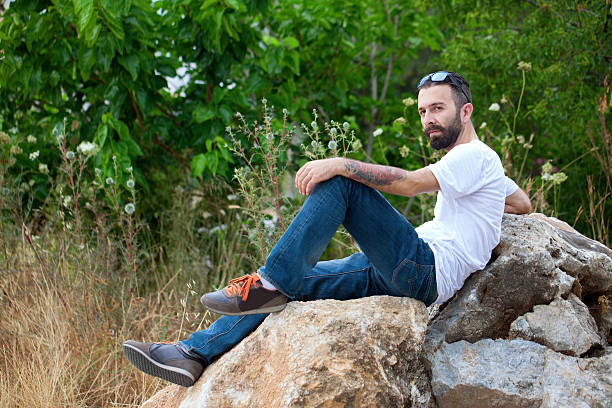 istock Bearded young man sitting on the rock enjoying the view 543598722