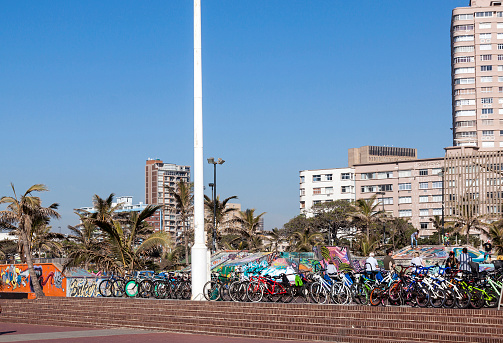 DURBAN, South Africa - June 26, 2016: Early morning empty promenade and stacked for hire bicycles against city skyline on beach front in Durban, South Africa