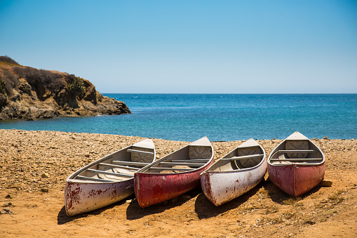 Four weathered canoes sitting on a quiet rocky beach on Catalina Island.