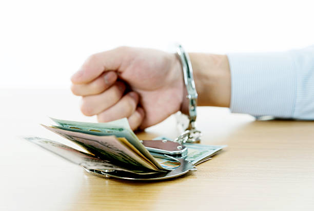 Businessman hands in handcuffs holding US dollars