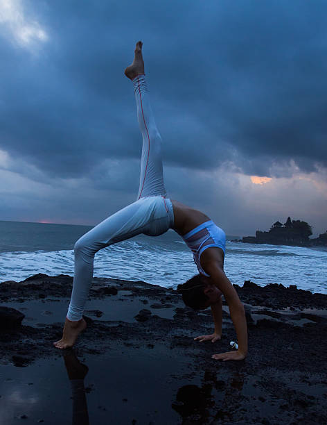 Yoga Young woman practicing yoga on the beach at sunset near Tanah Lot temple. Bali tanah lot sunset stock pictures, royalty-free photos & images