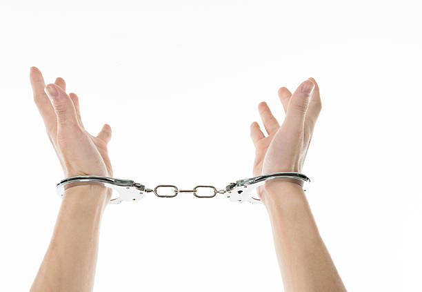 Close-up of man's hands in handcuffs isolated on white background.
