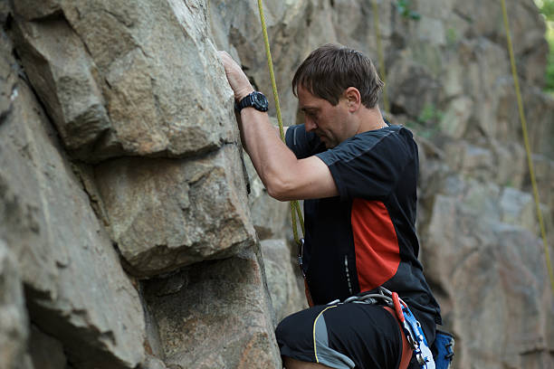 istock Male rock climber clings to a cliff 543655994