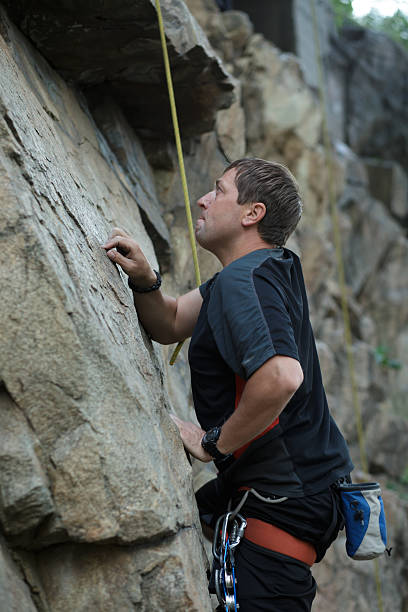 istock Male rock climber clings to a cliff 543656062