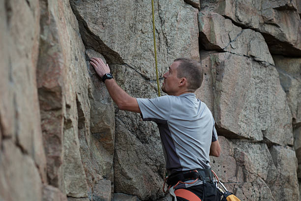 istock Male rock climber clings to a cliff 543656414