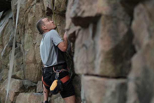 istock Male rock climber clings to a cliff 543656934