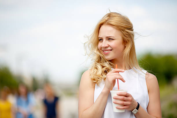 istock Blonde with drink in hand in sunny windy day looking 543659042