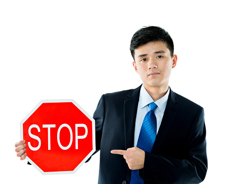 Young businessman holding STOP sign against white background.