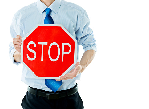 Businessman holding STOP sign against white background.