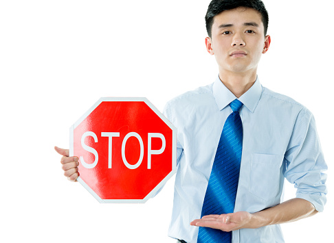 Young businessman holding STOP sign against white background.